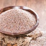 Flohsamenschalen in einer Schale mit Glas Wasser zur Einnahme